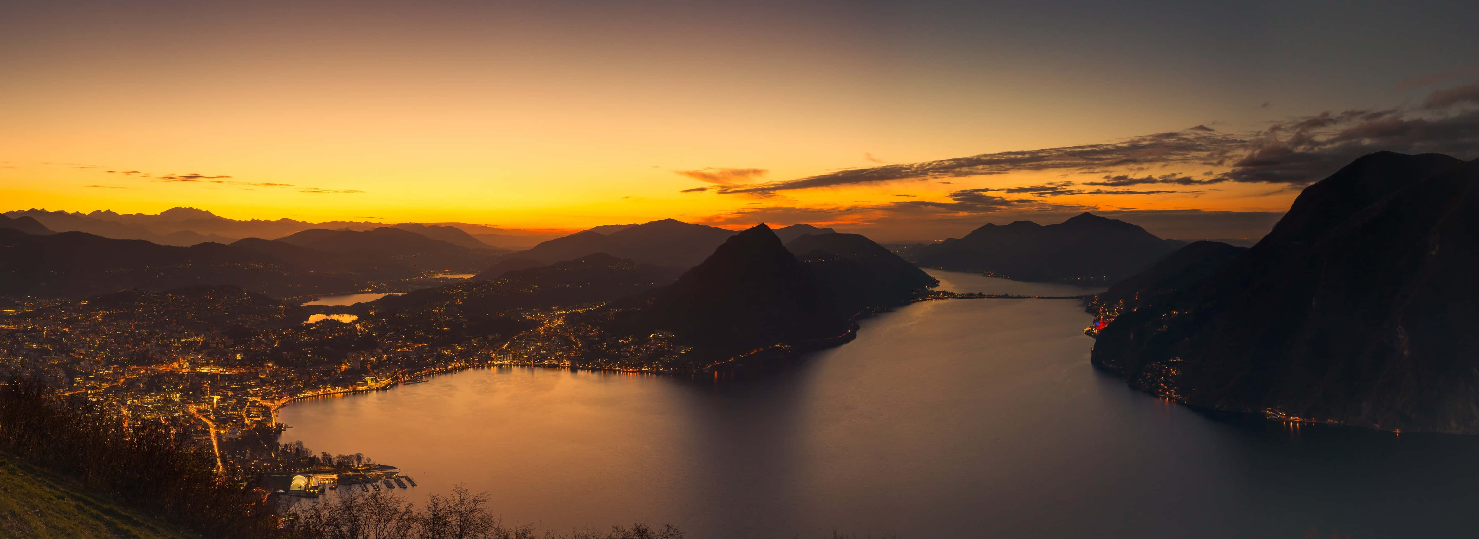 A Sunset Over A Lake And Mountains Wallpaper