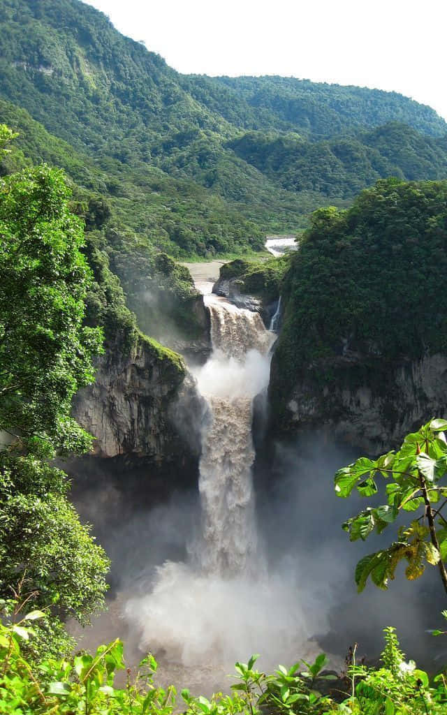 A Waterfall In The Middle Of A Lush Green Jungle Wallpaper