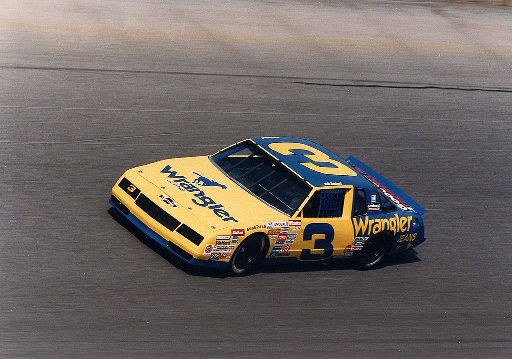 A Yellow And Blue Nascar Car Driving On A Track Wallpaper