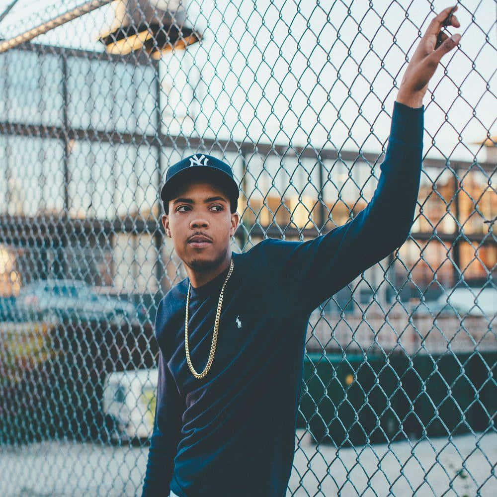 A Young Man Leaning Against A Chain Link Fence Wallpaper