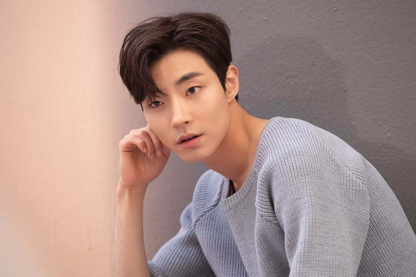 A Young Man Leaning Against A Wall Wallpaper