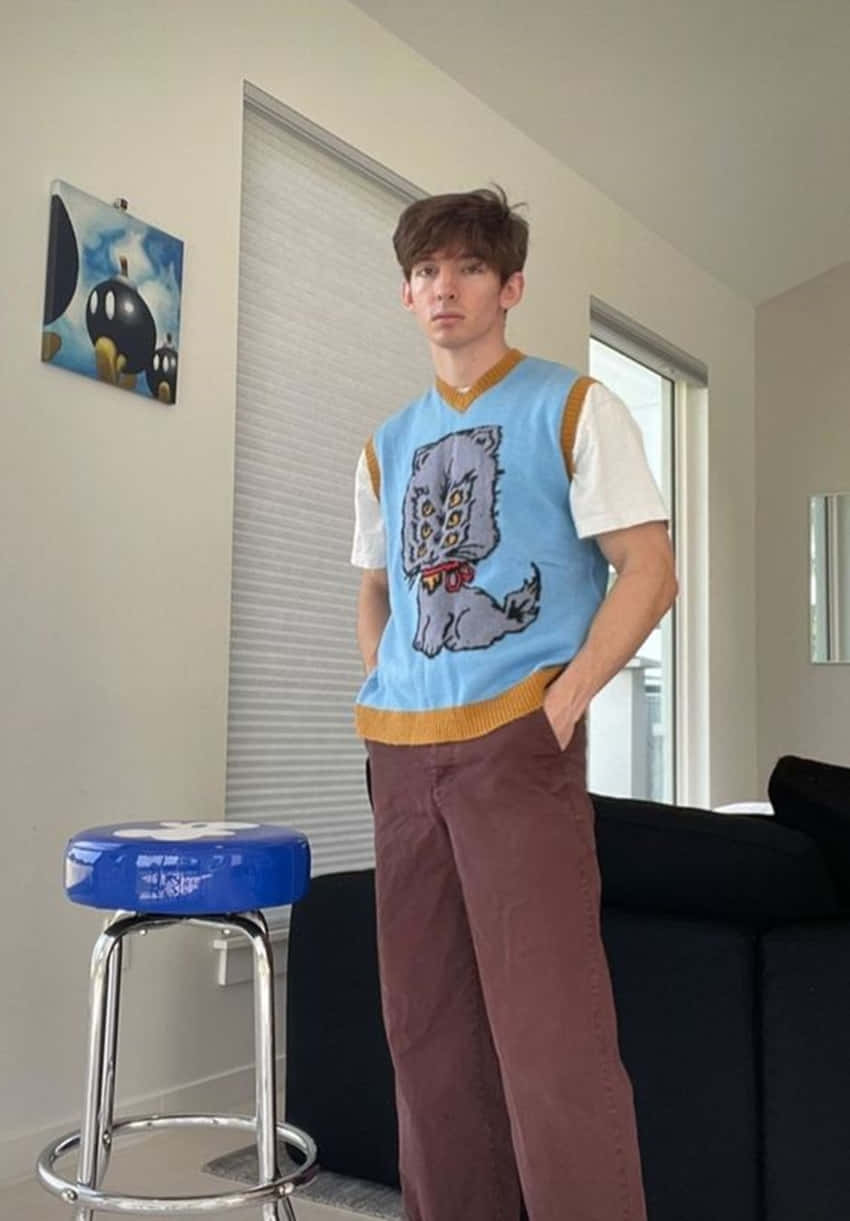 A Young Man Standing In Front Of A Couch Wallpaper