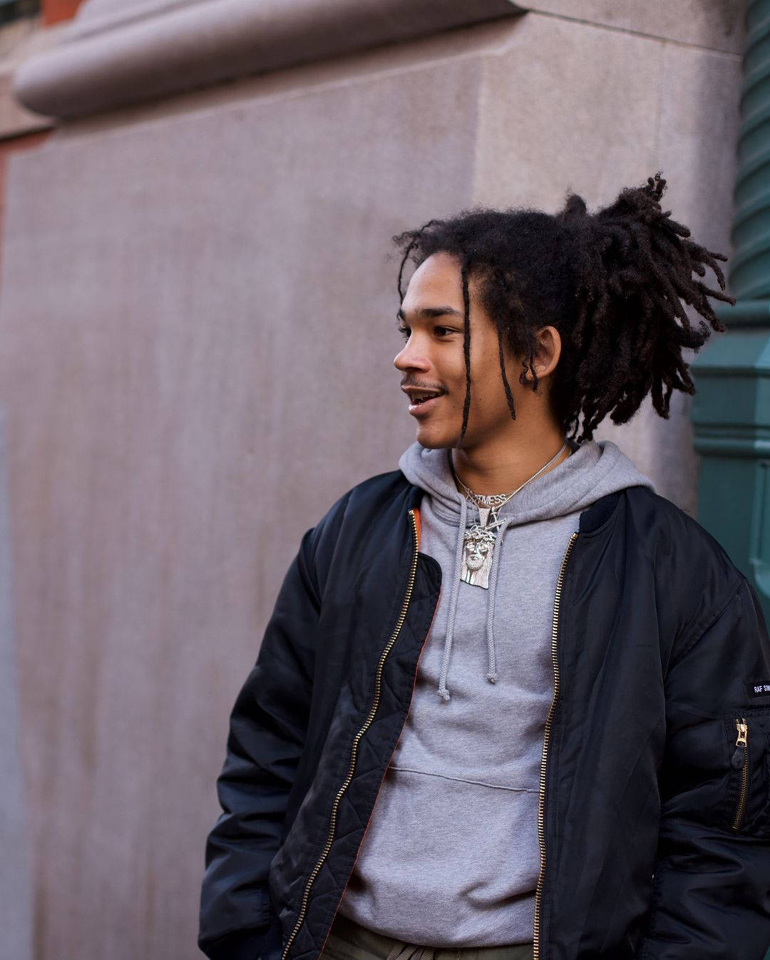 A Young Man With Dreadlocks Standing On A Street Wallpaper