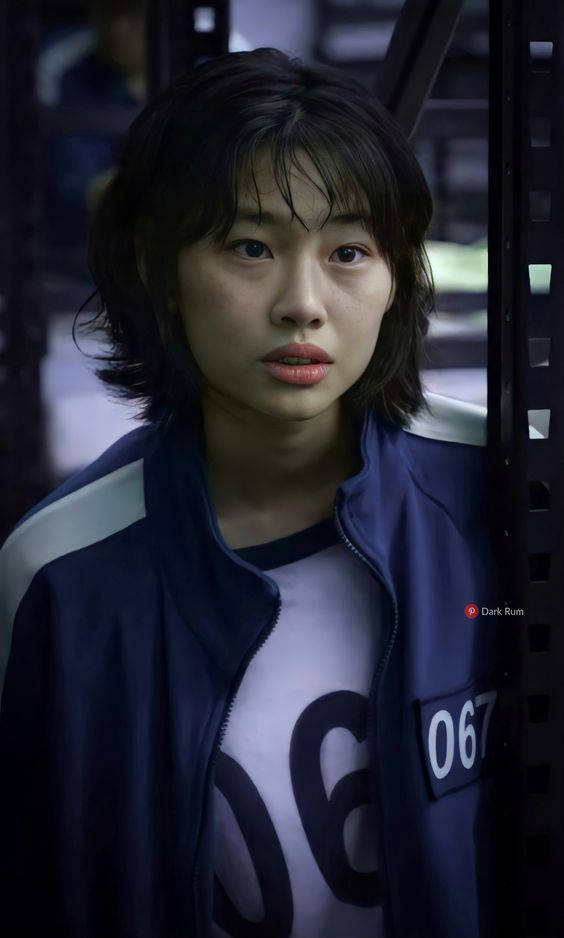 A Young Woman In A Blue Shirt Standing In A Jail Cell Wallpaper