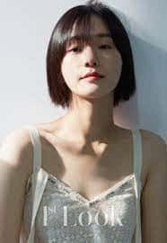 A Young Woman In A White Dress Posing Against A Wall Wallpaper