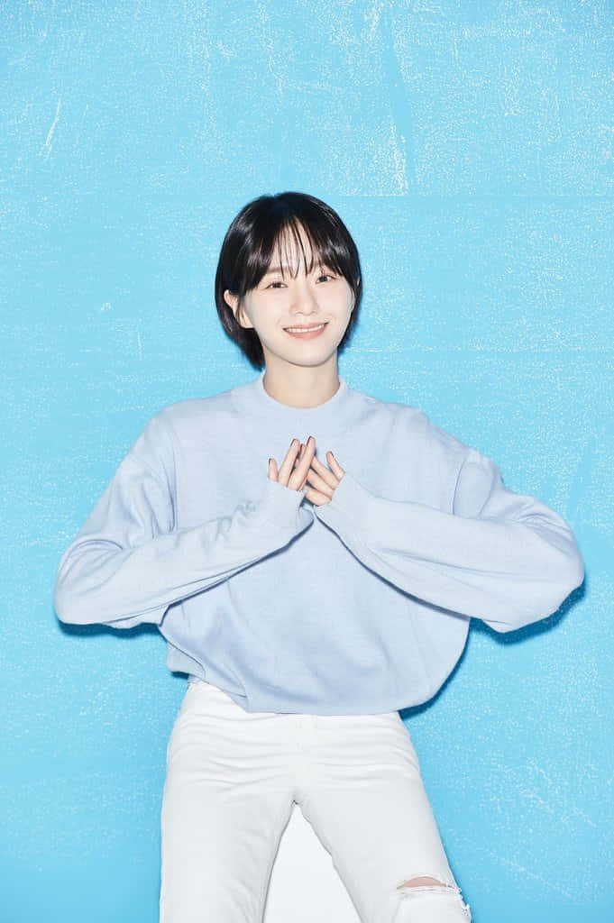 A Young Woman Sitting On A Blue Wall Wallpaper