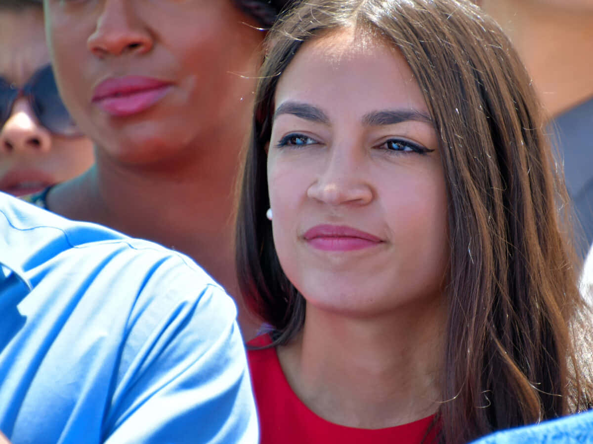 Alexandria Ocasio-cortez In Red Looking Towards Left Wallpaper