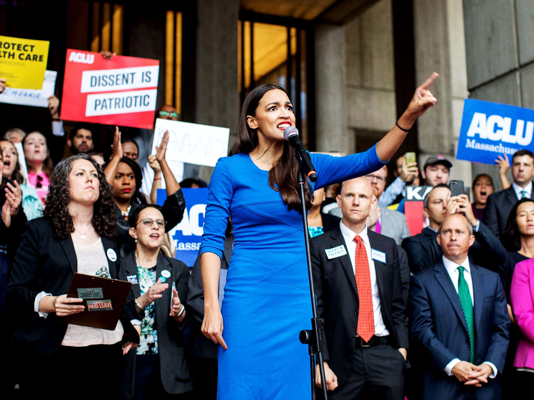 Alexandria Ocasio-cortez Wearing A Blue Dress Wallpaper