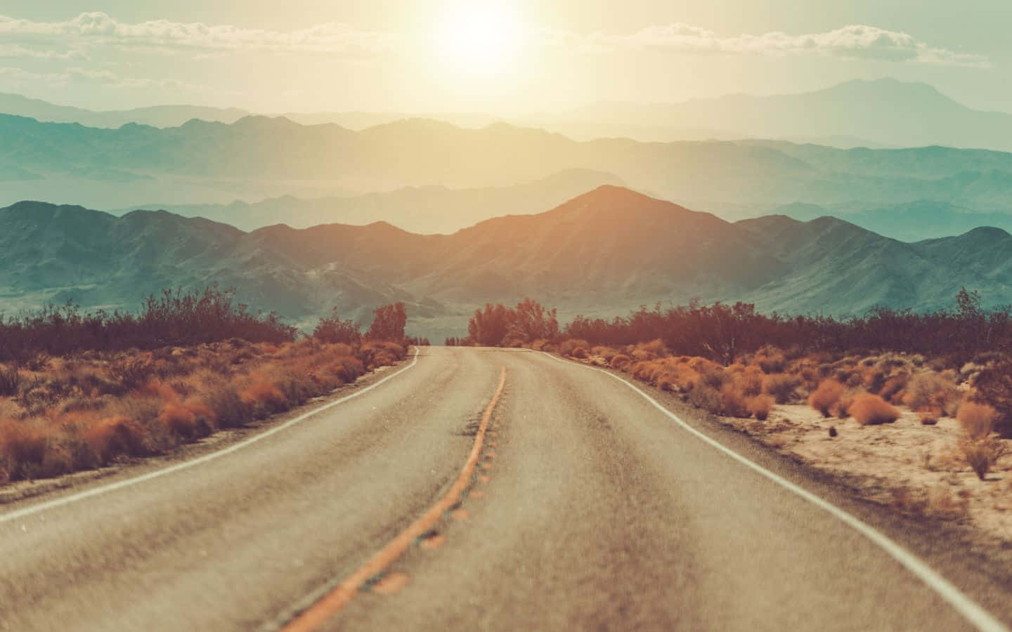 An Empty Road Leading Into The Desert At Sunset Wallpaper