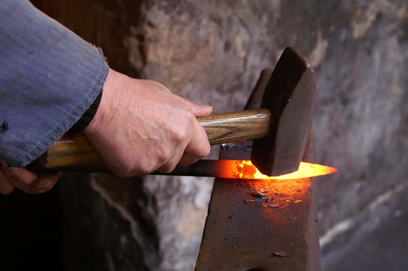 An Old-time Blacksmith Works Away At His Anvil Wallpaper