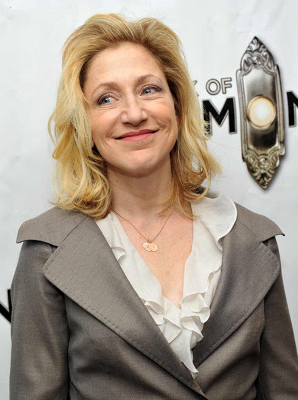 Award-winning Actress Edie Falco In Grey Suit Over White Ruffle Top Wallpaper