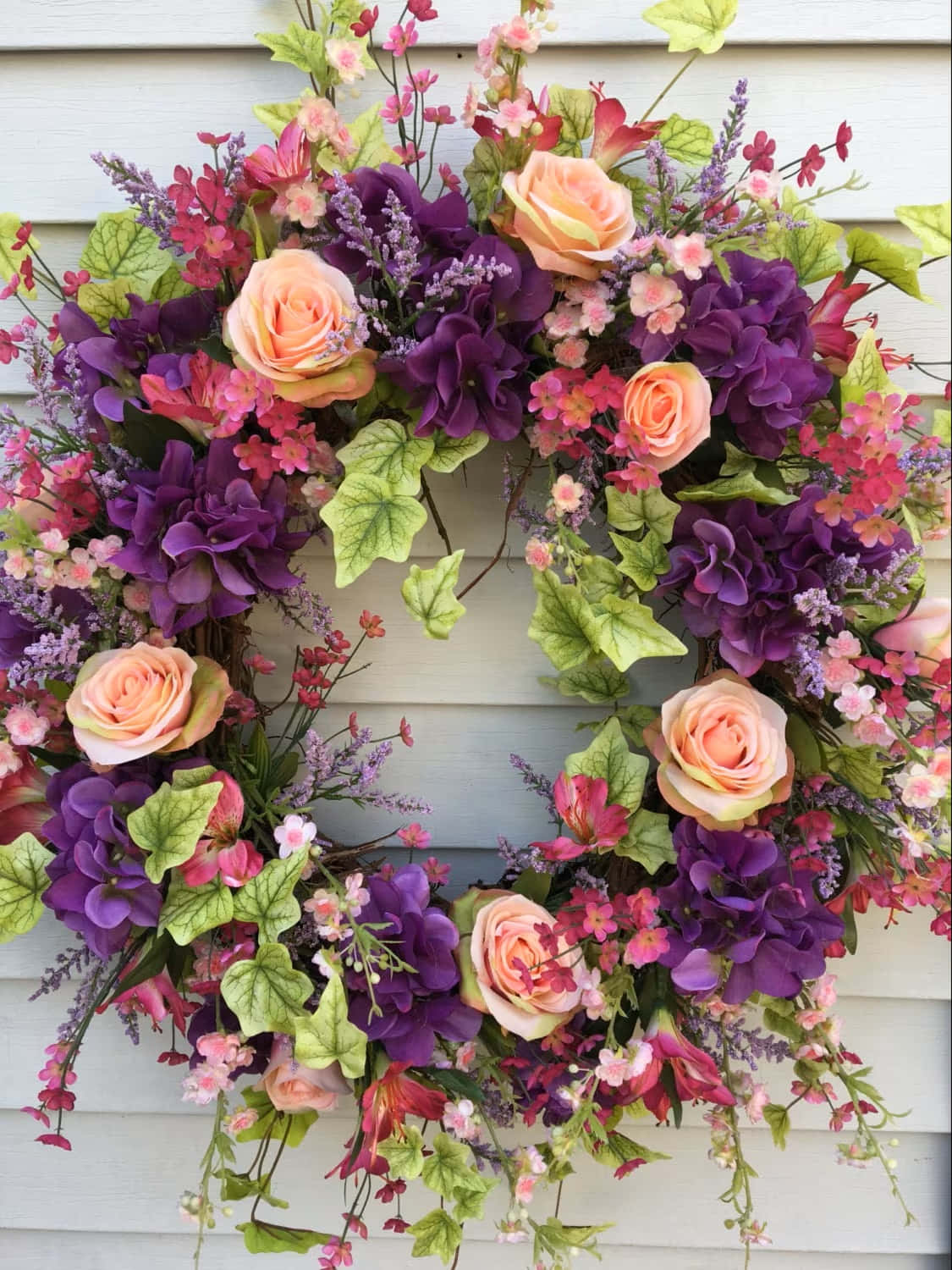 Beautiful Spring Wreath With Colorful Flowers Hanging On The Wooden Door Wallpaper