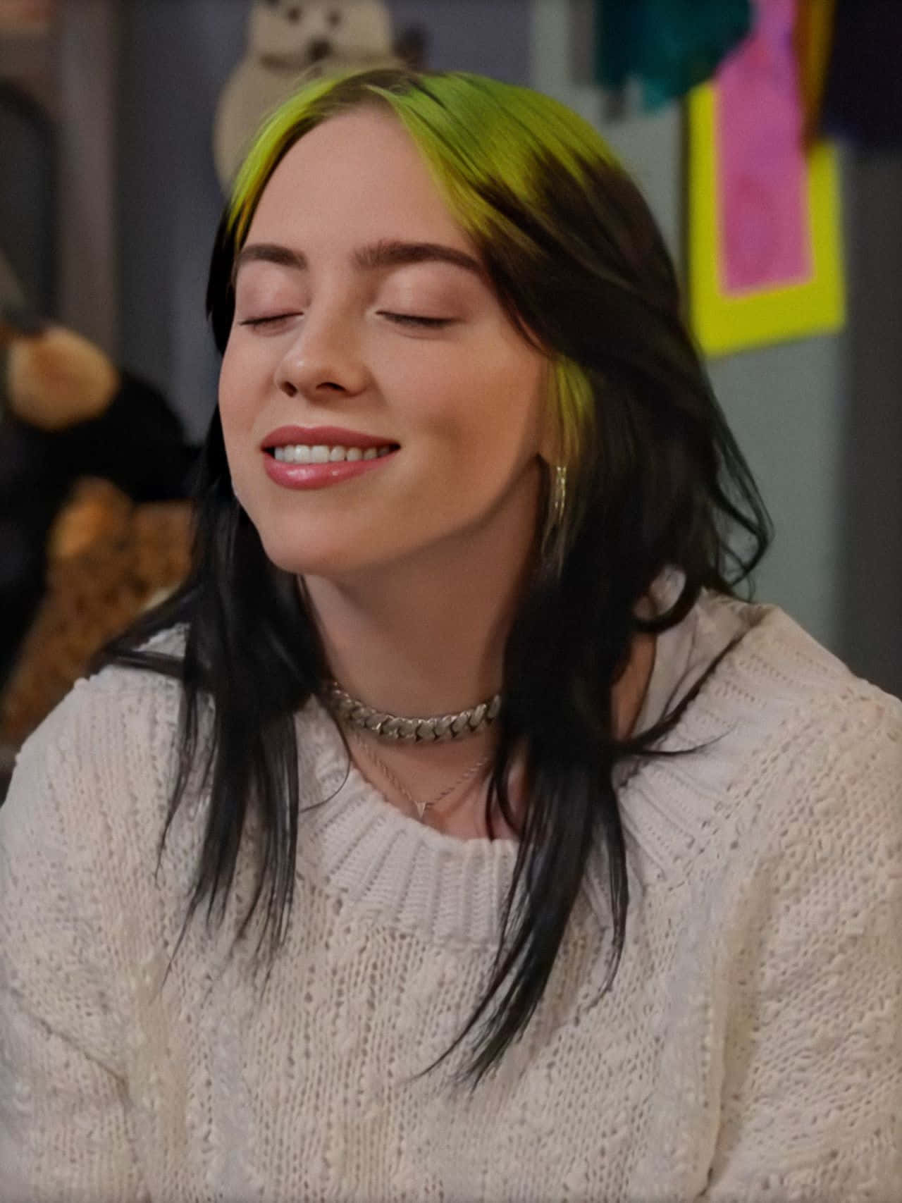 Billie Eilish Smiling With Her Signature Black And Green Hair Wallpaper