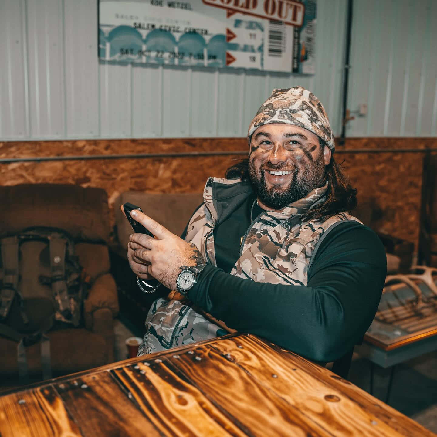 Camo Capped Man Smiling With Phone Wallpaper