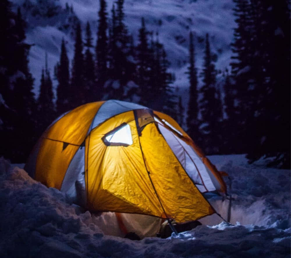 Caption: A Cozy Winter Camping Setup In A Snowy Forest Wallpaper