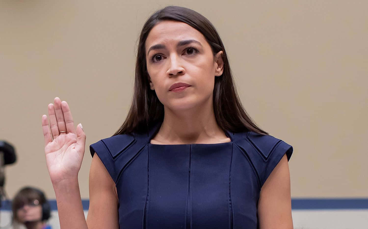 Caption: Alexandria Ocasio-cortez Raising Her Hand In Passionate Speech Wallpaper