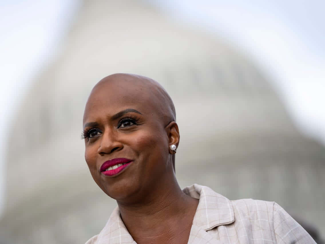 Caption: Ayanna Pressley Standing Strong Against Blurred Backdrop Of The Capitol Wallpaper