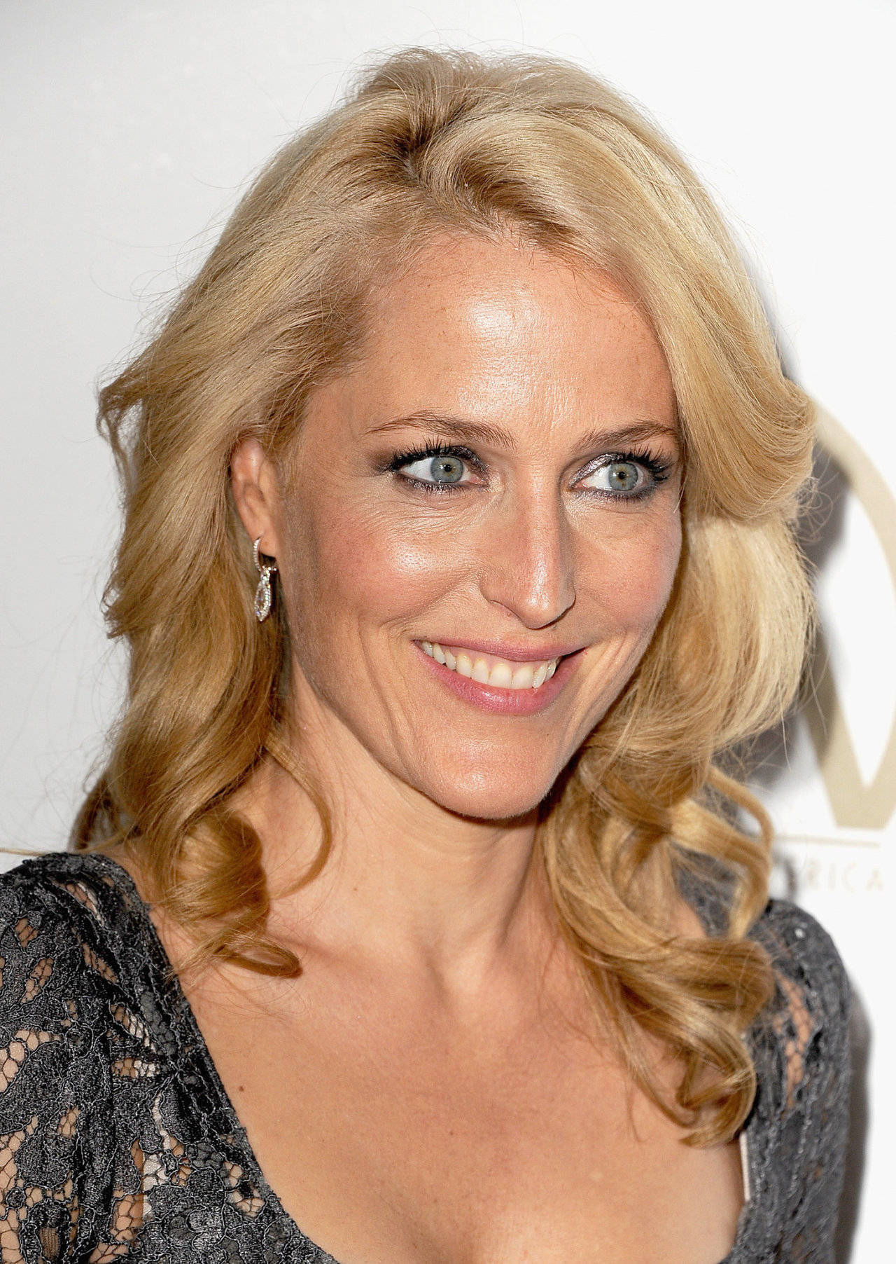 Caption: Gillian Anderson Showcasing A Curly Blonde Hairstyle. Wallpaper