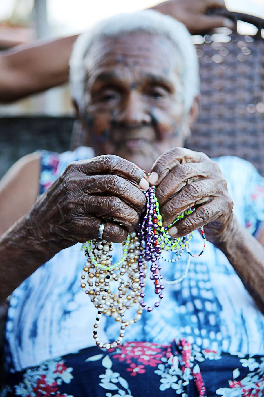 Caption: Graceful Elderly Woman Admiring Her Bead Bracelet Wallpaper