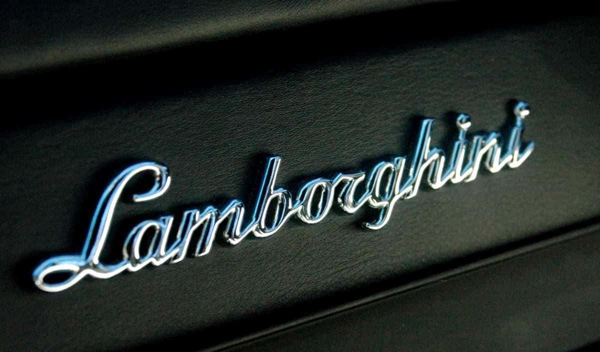 Caption: Iconic Car Logo On A Shimmering Metallic Background Wallpaper