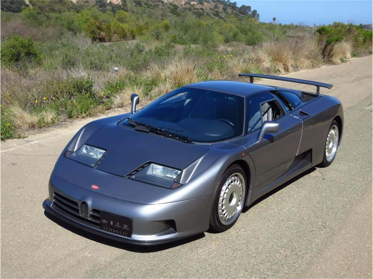 Caption: Sleek Bugatti Eb110 On A Scenic Road Wallpaper