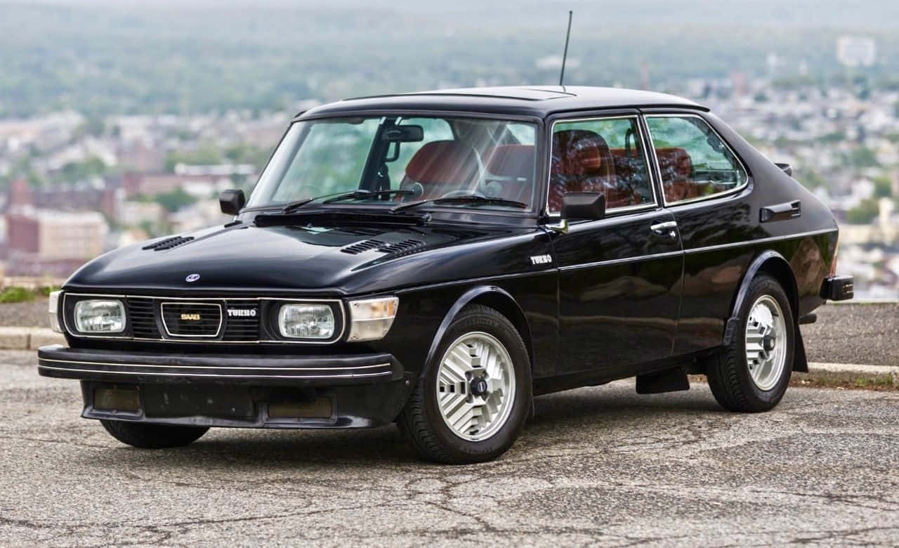 Caption: Stunning Vintage Saab 99 Turbo In Nature Wallpaper