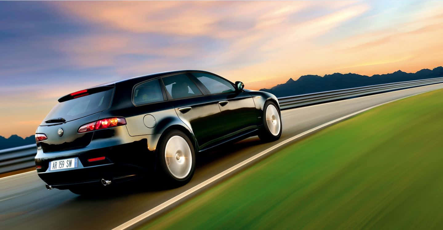 Captivating Alfa Romeo 159 Sports Sedan On A Scenic Highway Wallpaper