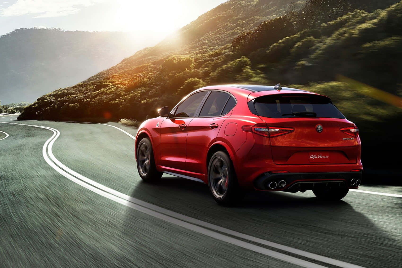 Captivating Alfa Romeo Stelvio On A Scenic Mountain Road Wallpaper