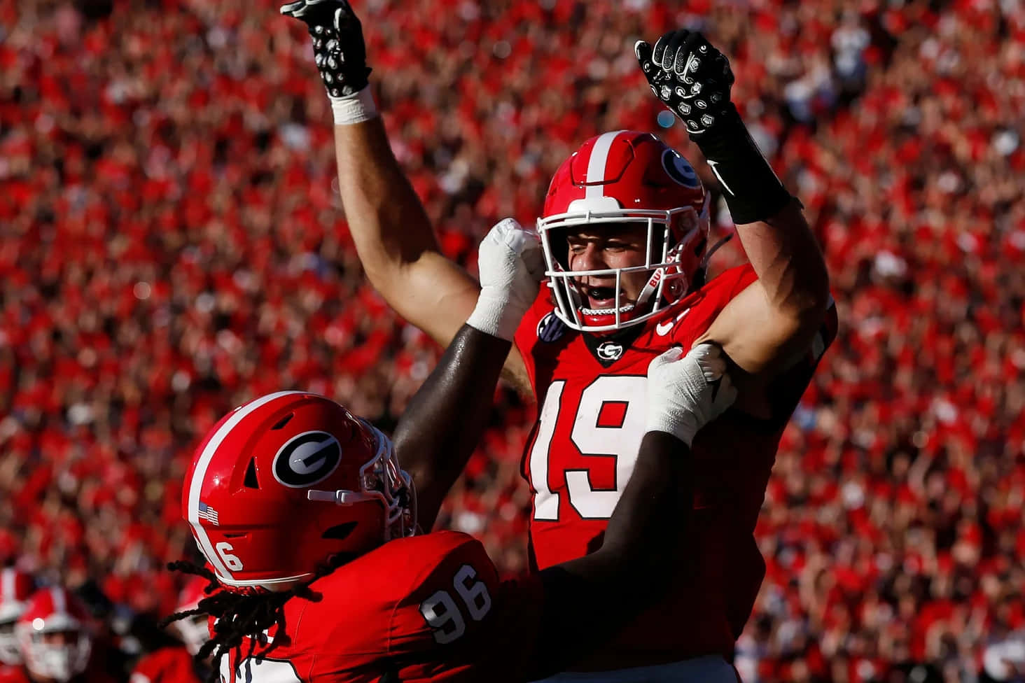 Celebratory Football Player Liftedby Teammate Wallpaper