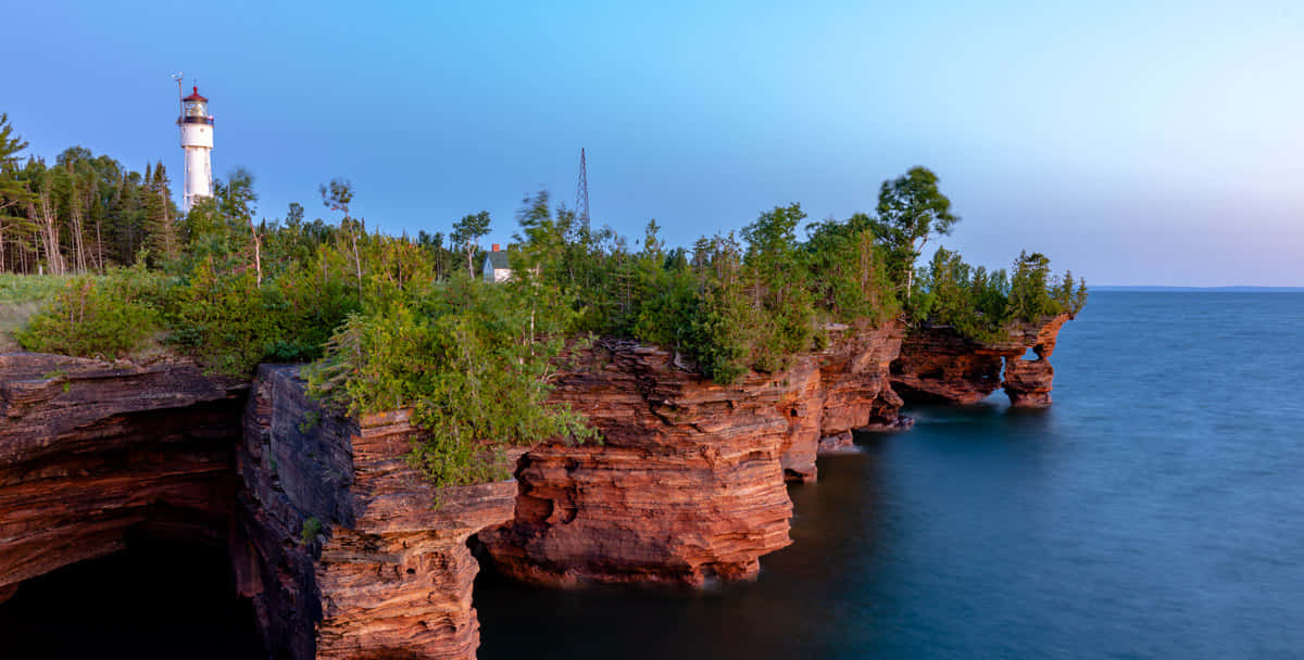 Coastal Lighthouse Over Sea Caves Wallpaper