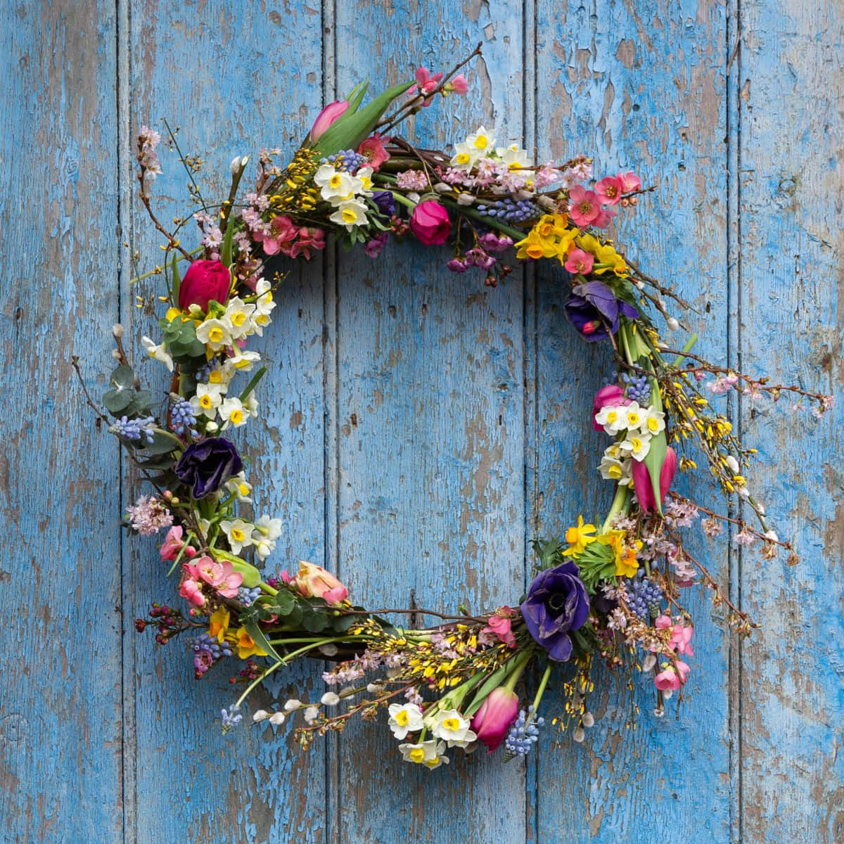 Colorful Spring Wreath With Vibrant Flowers On Wooden Door Wallpaper