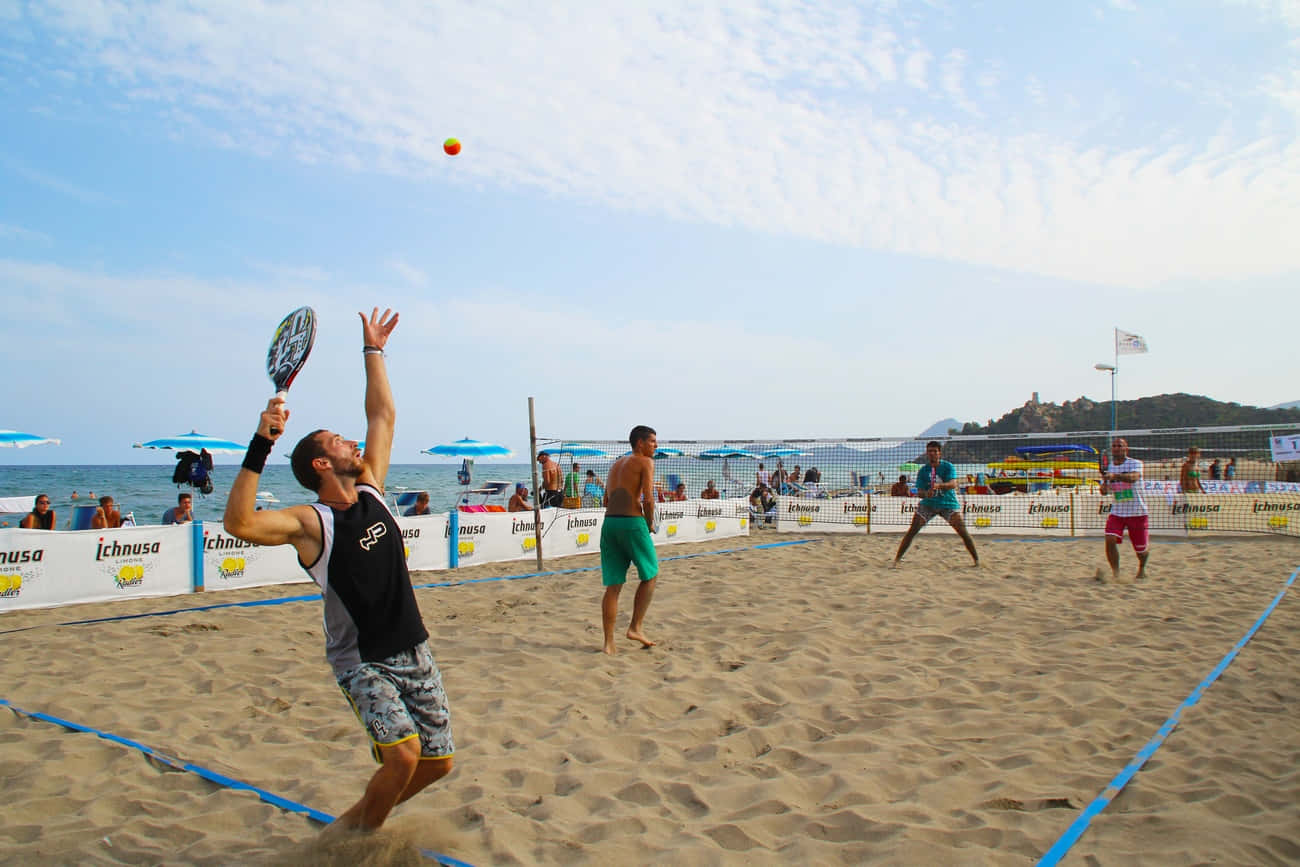 Competitive Beach Tennis Match Under The Clear Blue Sky Wallpaper