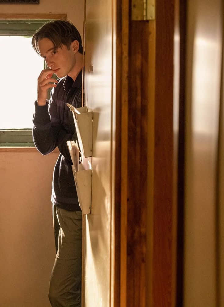 Contemplative Young Man Leaning Against Doorframe Wallpaper