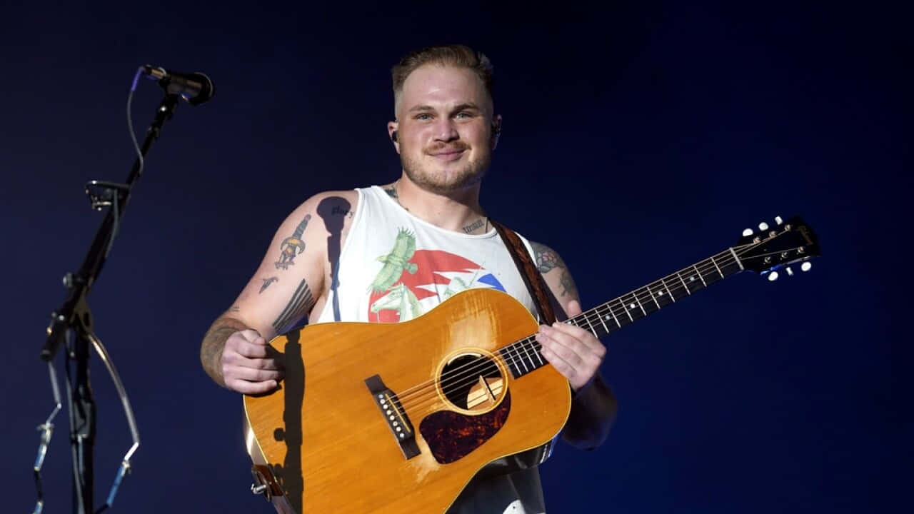 Country Musician With Guitar On Stage Wallpaper