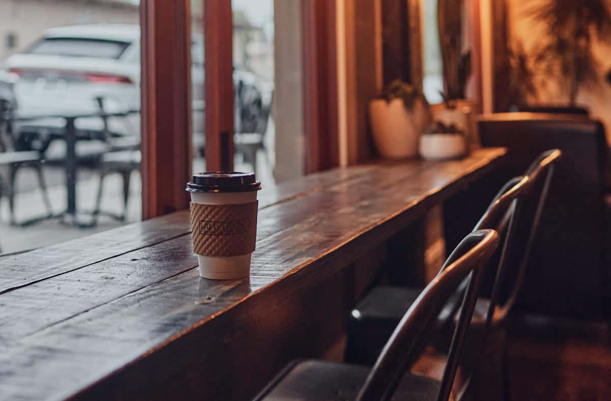 Cozy Coffee Shop Interiorwith To Go Cup Wallpaper