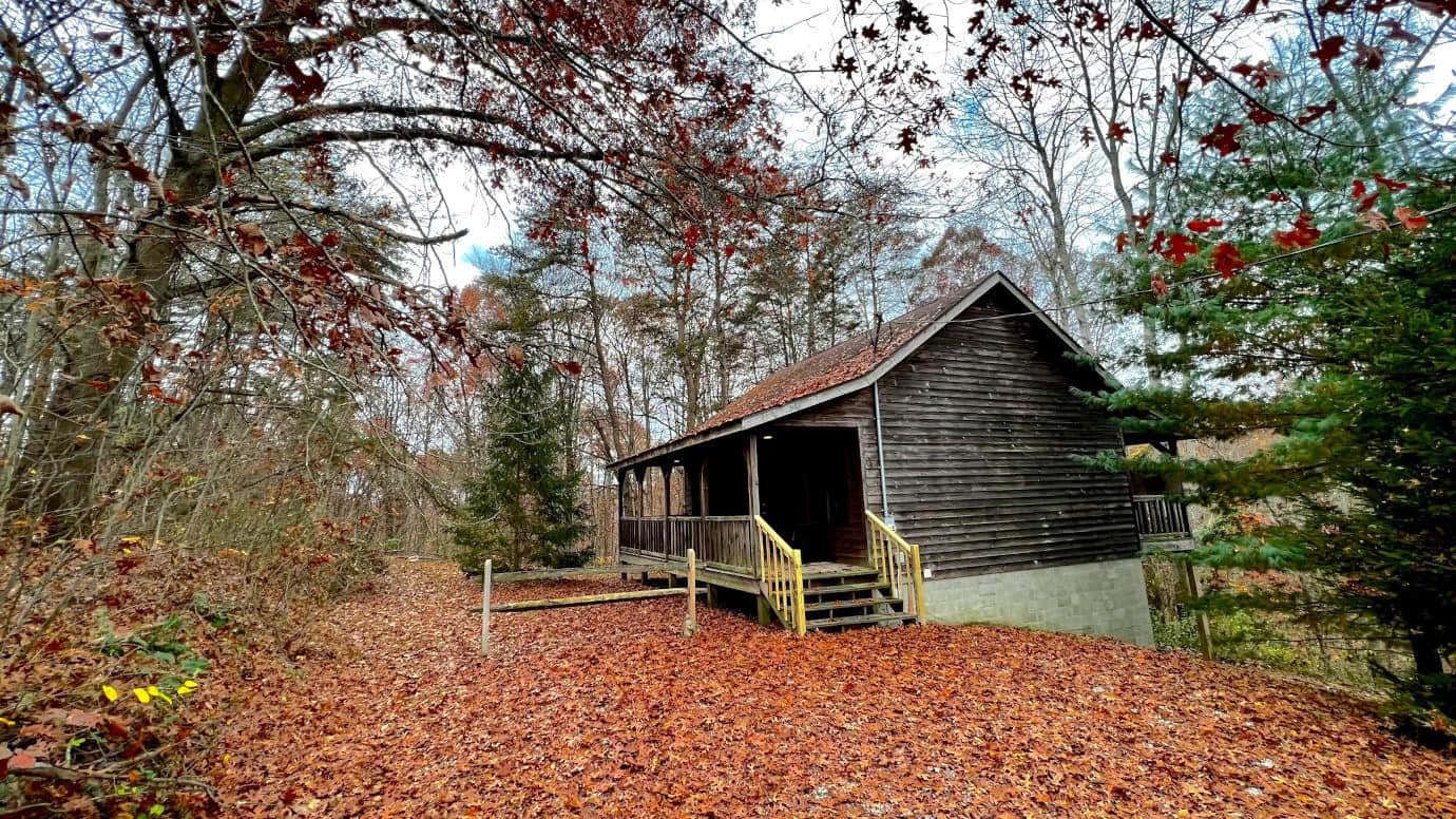 Cozy Fall Cabin Surrounded By Vibrant Autumn Foliage Wallpaper