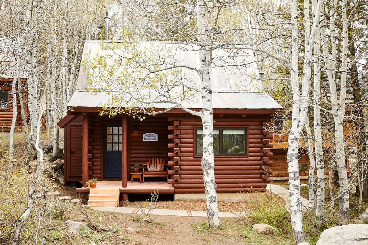 Cozy Fall Cabin Surrounded By Vibrant Autumn Foliage Wallpaper