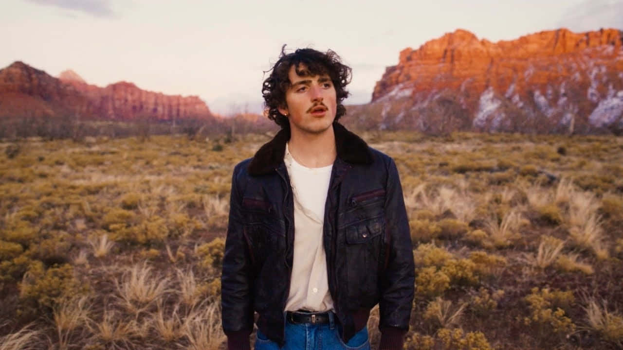 Curly Haired Man In Desert Landscape Wallpaper