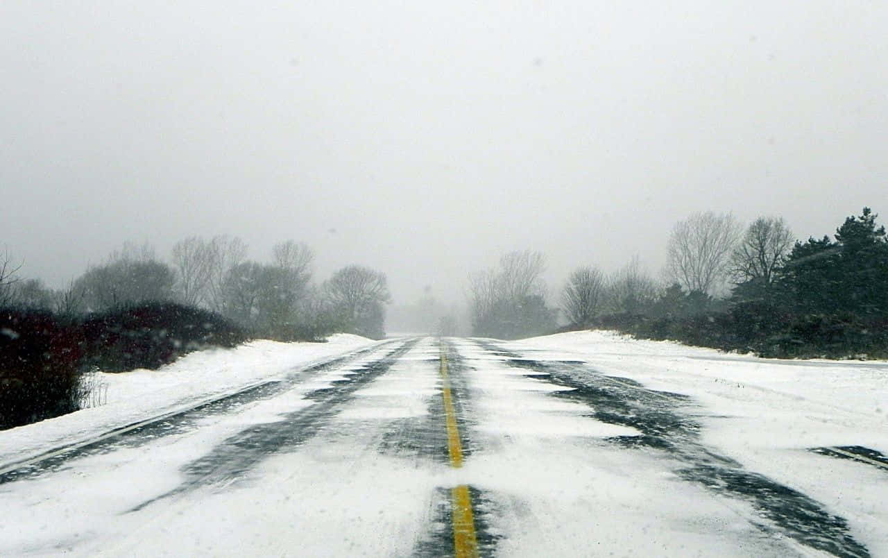 Dangerous Icy Road Surrounded By Snowy Trees Wallpaper