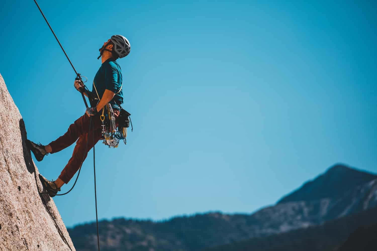 Daring Adventurer Standing On A Mountain Cliff Wallpaper