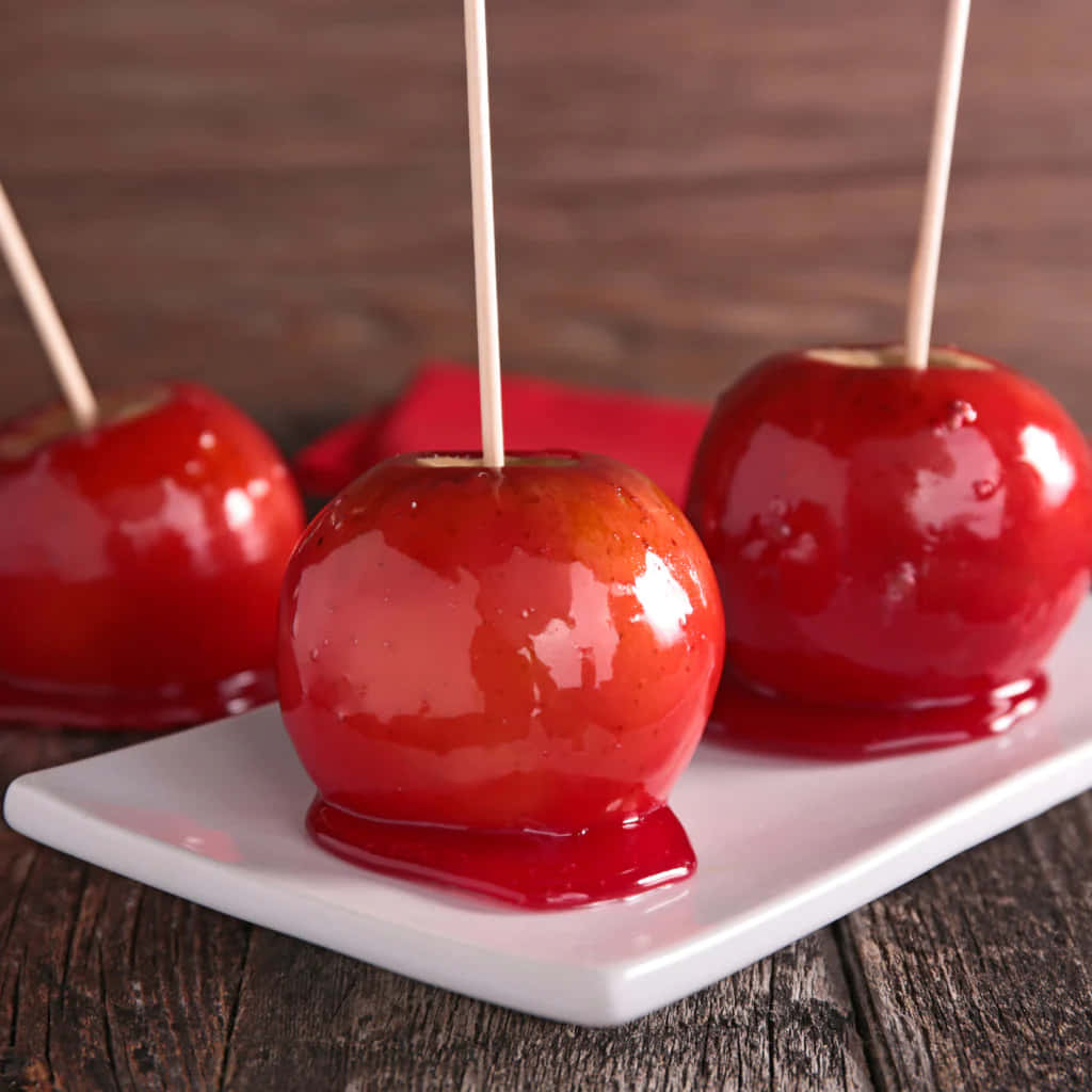 Delicious Red Candy Apples On Wooden Table Wallpaper