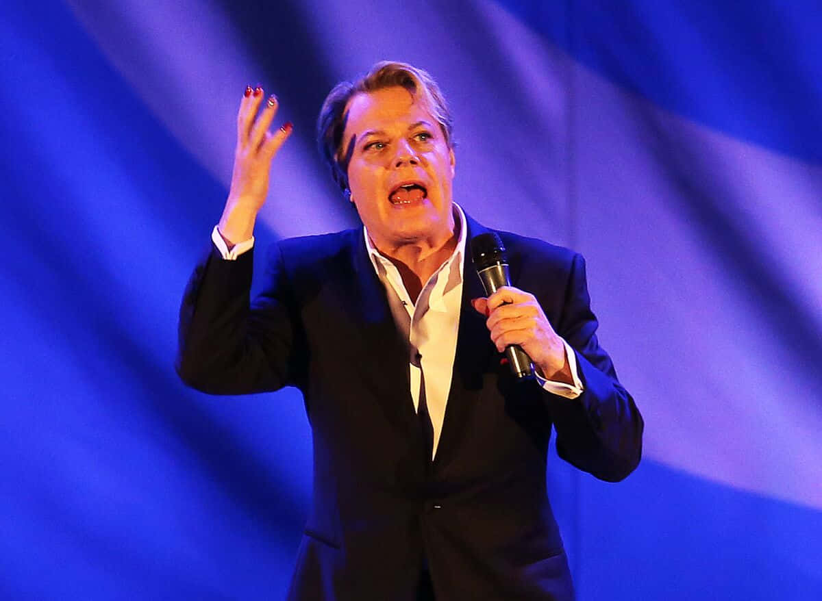 Eddie Izzard Captivating The Audience With His Comedic Performance Wallpaper