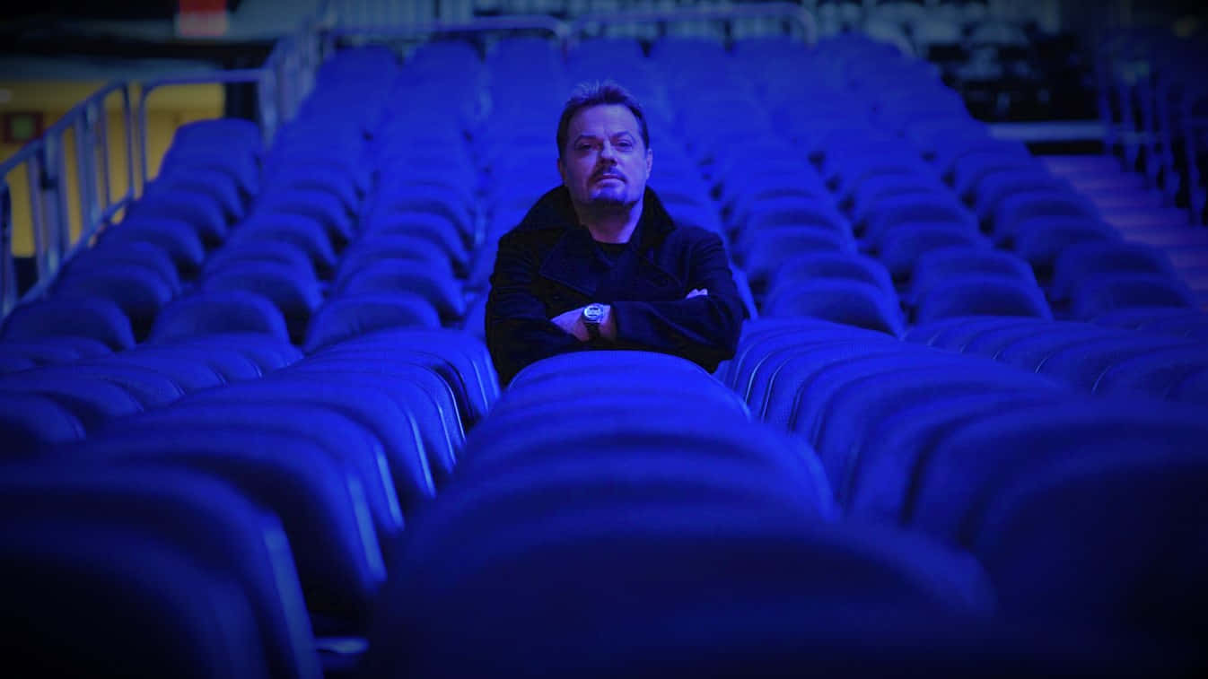 Eddie Izzard Posing On Stage During A Live Performance Wallpaper