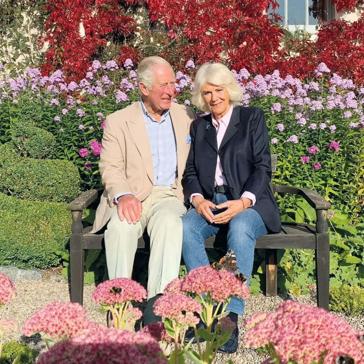 Elegance Embodied: Queen Camilla Poses Gracefully On Bench Wallpaper