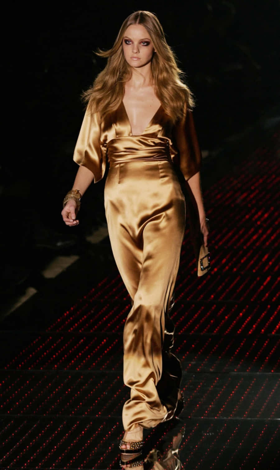 Elegant Modelin Golden Satin Dress Walkingon Runway Wallpaper