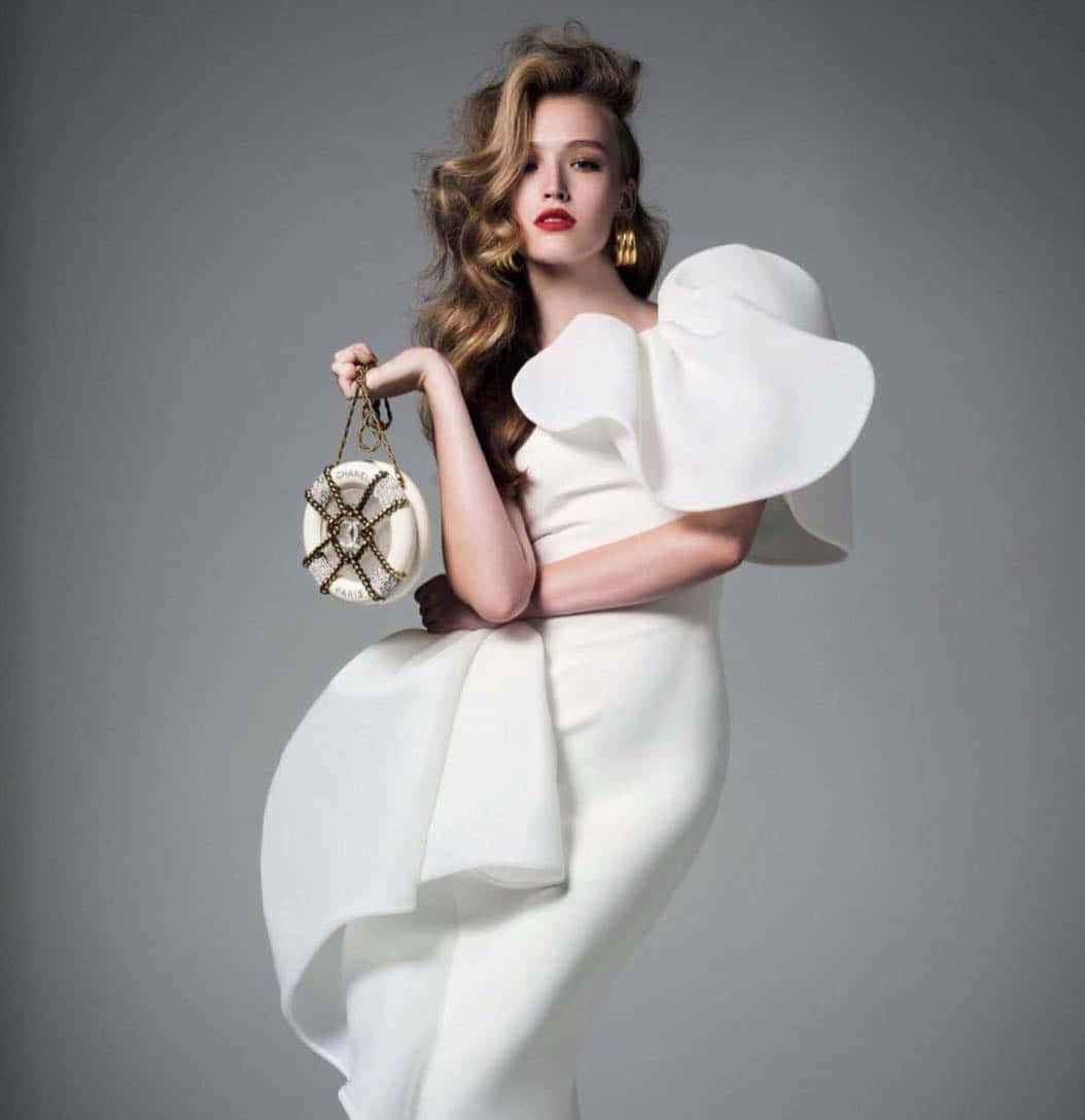 Elegant Modelin White Dresswith Designer Bag Wallpaper