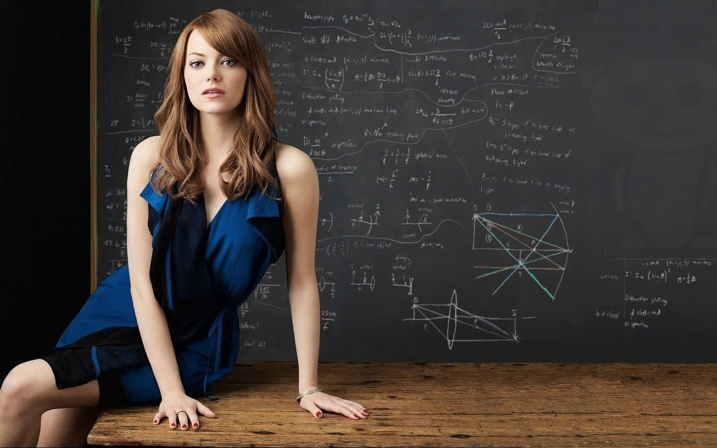 Emma Stone In A Blue Dress Posing In Front Of A Blackboard Wallpaper