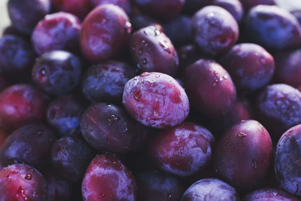 Enjoy A Healthy Bowl Of Fresh Purple Plums Wallpaper