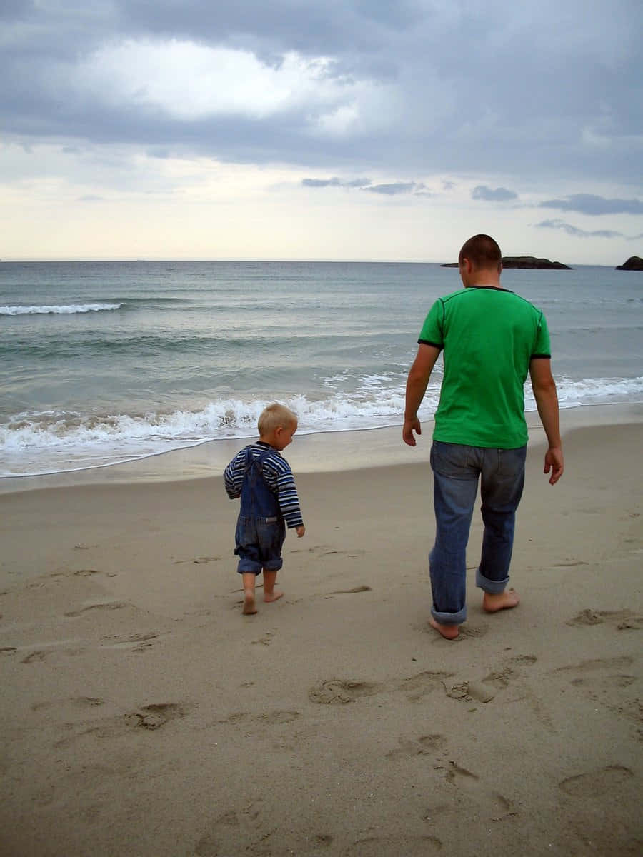 Enjoying A Serene Beach Walk At Sunset Wallpaper