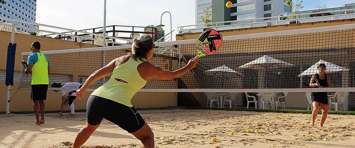 Exciting Beach Tennis Match On A Sunny Day Wallpaper